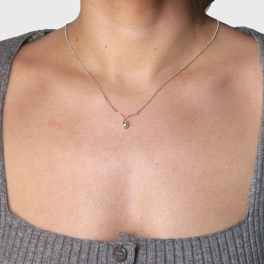 Een zilver collier met een gewikkeld pareltje