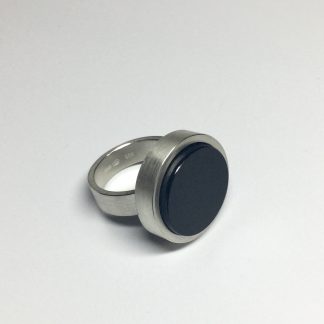 foto van een zilveren ring met een ronde zwarte onyx edelsteen.